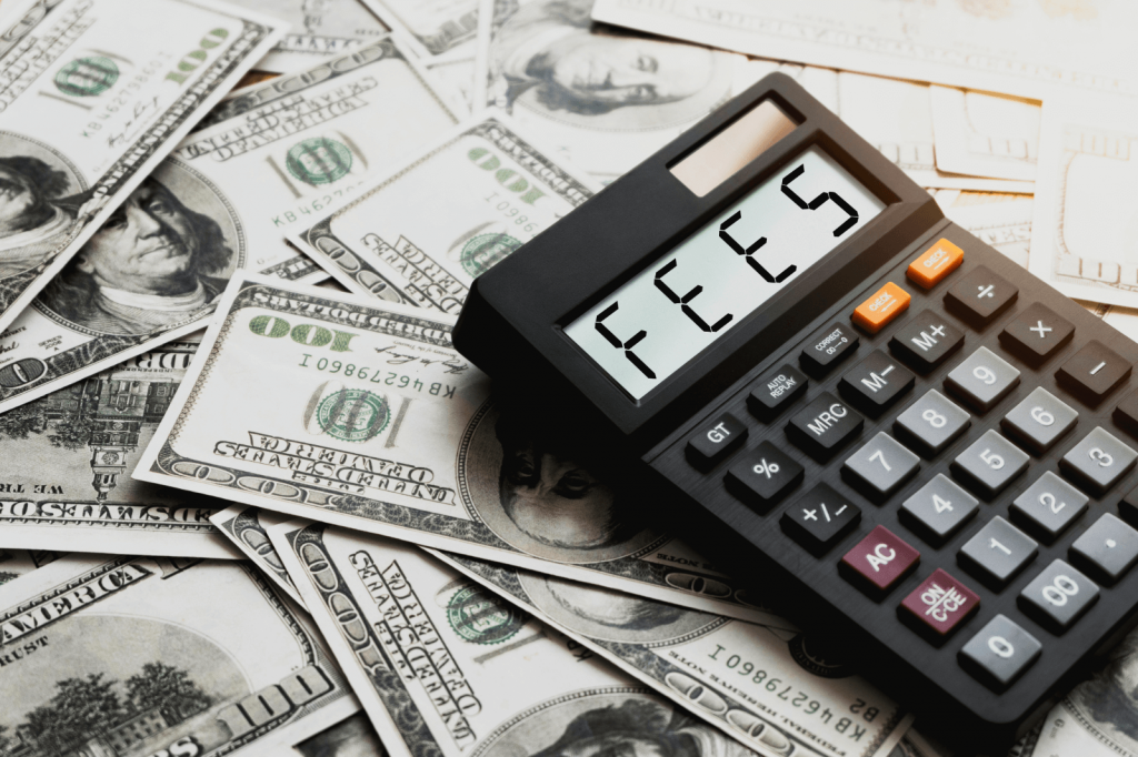 Calculator displaying the word "Fees" on a background of dollar bills