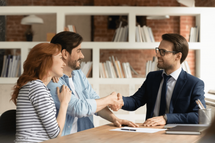 Couple shaking hands with a banker after securing a loan