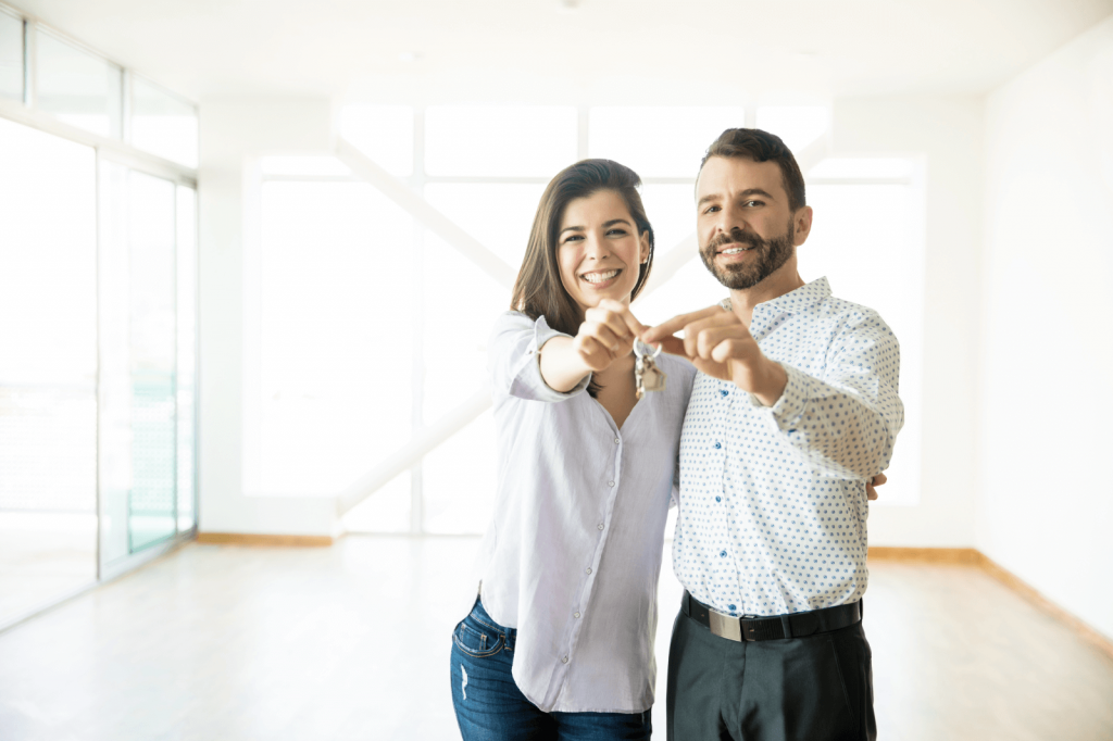 Happy couple holding house keys in their new home