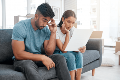 A worried couple reviewing mortgage documents on their couch