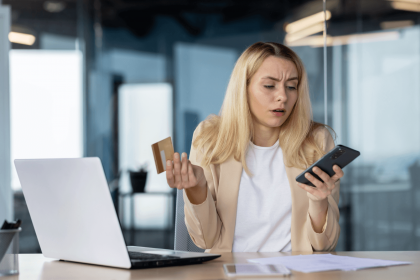 Worried woman looking at her phone while holding a credit card