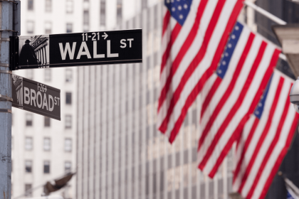 Tech stocks propel S&P 500 to record highs with Wall Street sign and American flags in the background