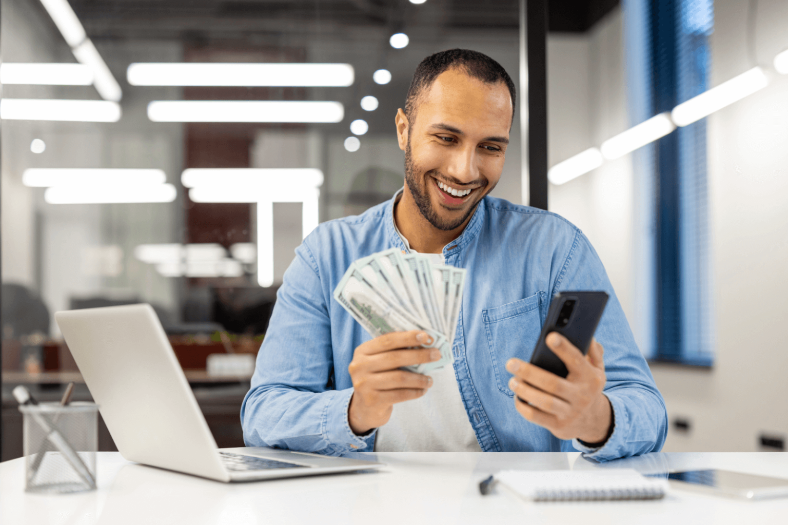 Man holding money and checking his phone.