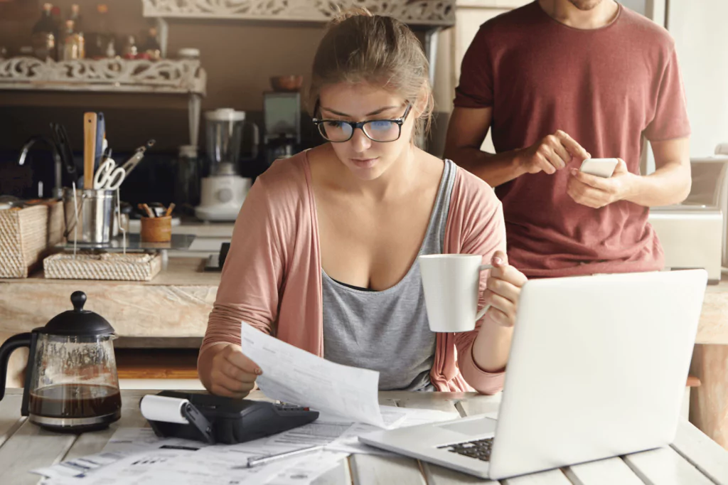 Woman managing finances at home with a laptop and documents.