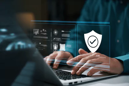 Hands typing on a laptop with cybersecurity and AI graphics.