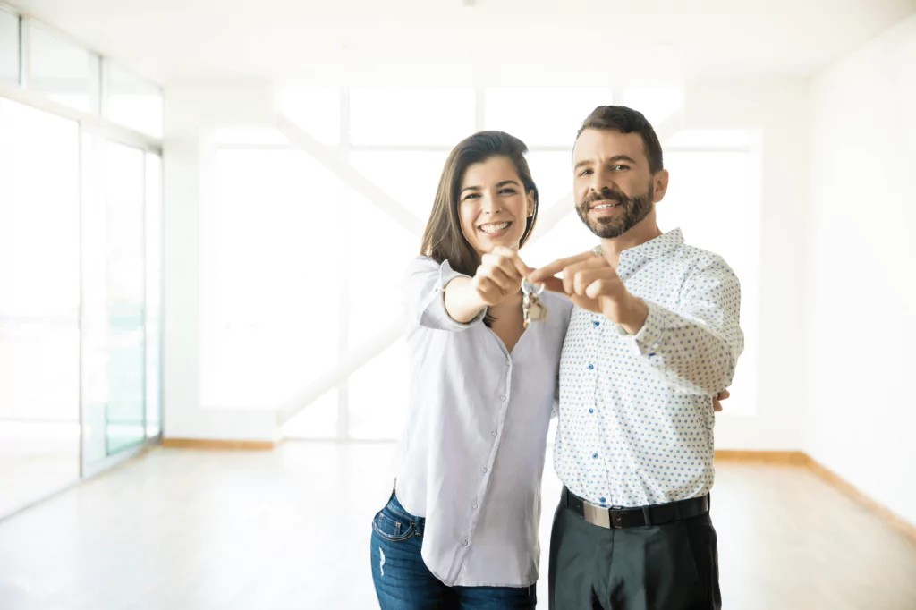 Happy couple holding house keys in their new home