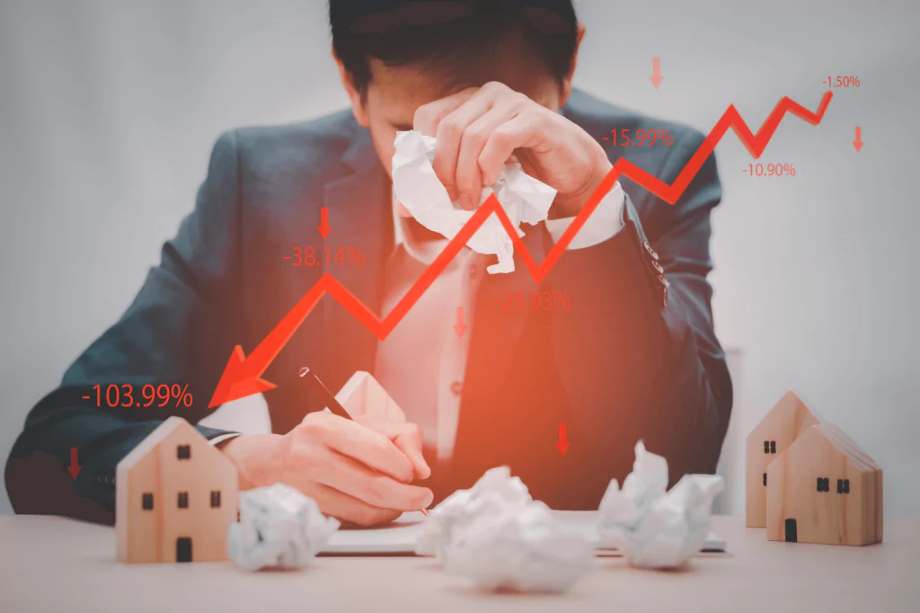 A man stressed with economic graphs and house models.