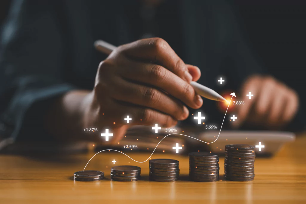 Hand with pen and stacked coins showing financial growth