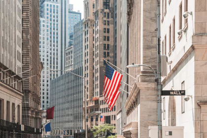 Wall Street with American flag, representing financial markets and economic activity.