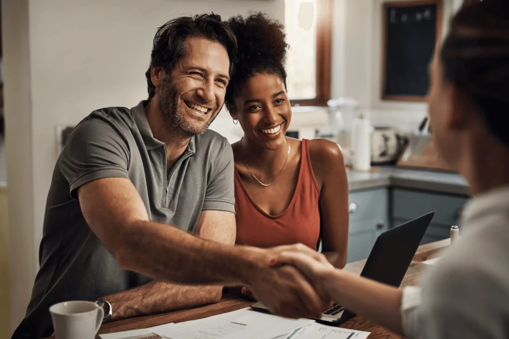 Happy couple shaking hands with a loan officer after securing a low-rate loan.