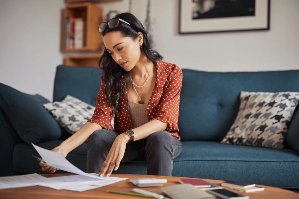 Woman sitting on a couch, reviewing loan documents.