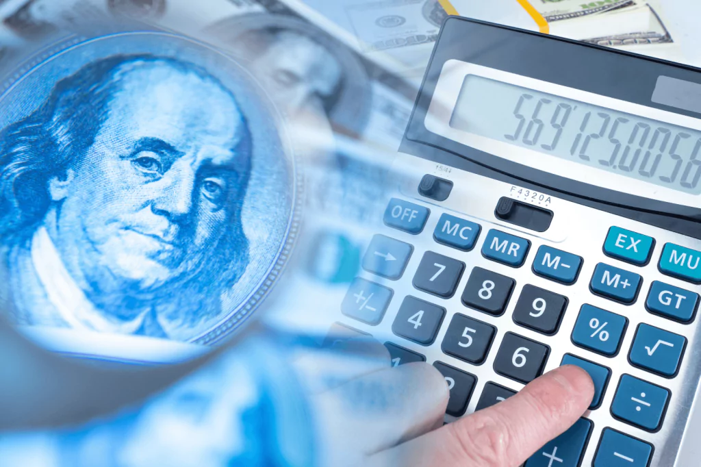 Calculator and Benjamin Franklin portrait on a dollar bill.